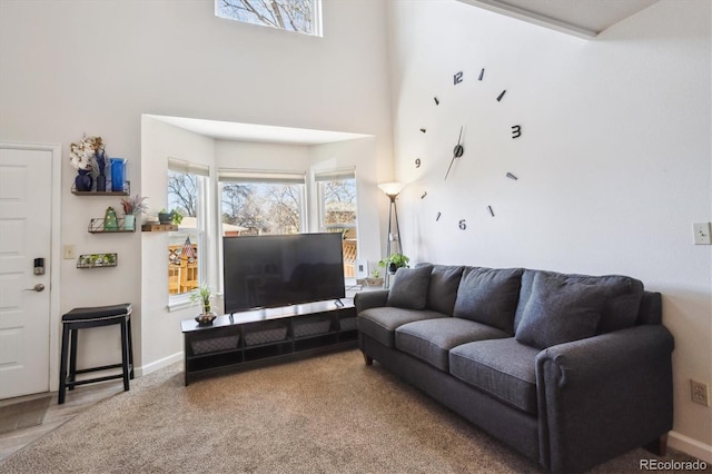 carpeted living area featuring baseboards and a towering ceiling