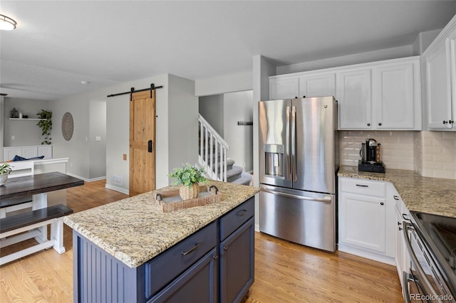11188 Latigo Ln, Parker, CO 80138 - kitchen with stainless steel appliances, a barn door, white cabinets, light wood-style floors, and a center island