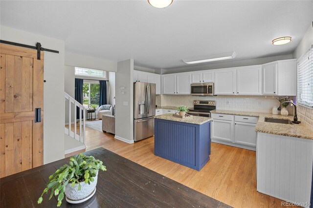 11188 Latigo Ln, Parker, CO 80138 - kitchen featuring appliances with stainless steel finishes, a sink, white cabinetry, light wood-style floors, and plenty of natural light