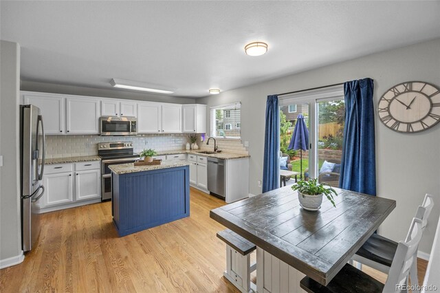 11188 Latigo Ln, Parker, CO 80138 - kitchen featuring appliances with stainless steel finishes, a center island, white cabinets, and backsplash