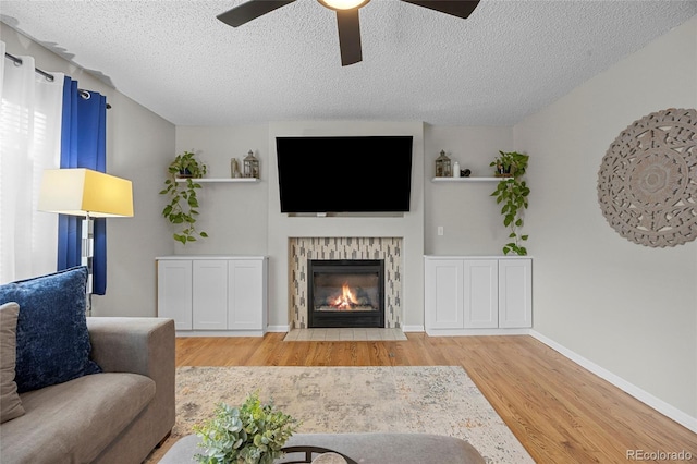 11188 Latigo Ln, Parker, CO 80138 - living area with ceiling fan, wood finished floors, a textured ceiling, a tiled fireplace, and baseboards