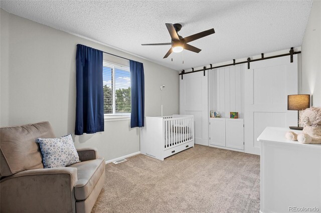 11188 Latigo Ln, Parker, CO 80138 - bedroom with a barn door, light colored carpet, a textured ceiling, heating unit, and a ceiling fan
