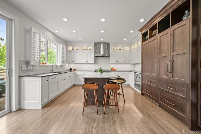2090 Bellavista St, Castle Rock, CO 80109 - kitchen featuring wall chimney exhaust hood, a sink, recessed lighting, light wood-style flooring, and a breakfast bar