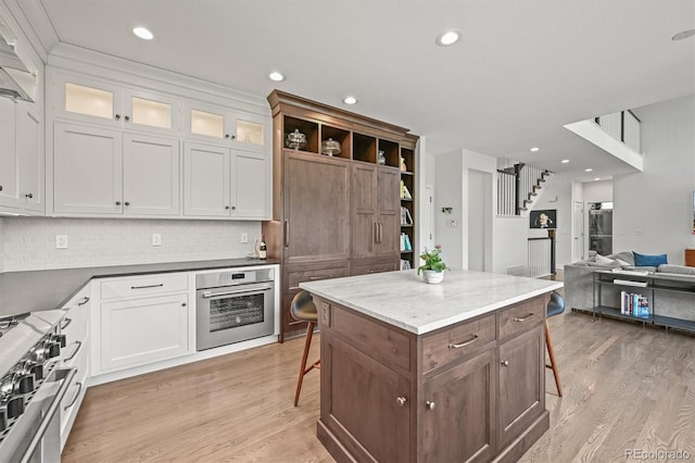2090 Bellavista St, Castle Rock, CO 80109 - kitchen featuring appliances with stainless steel finishes, a kitchen bar, light wood-type flooring, white cabinetry, and recessed lighting