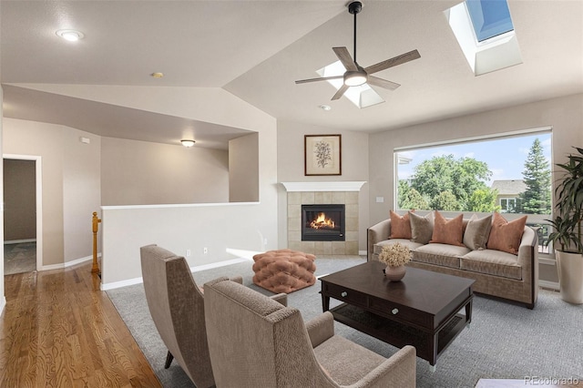 149 Walters Creek Dr, Monument, CO 80132 - living room featuring vaulted ceiling, wood finished floors, a ceiling fan, a tile fireplace, and a skylight