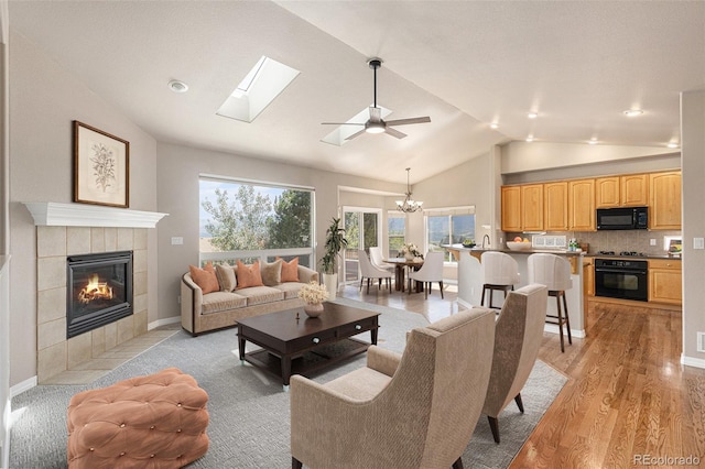 149 Walters Creek Dr, Monument, CO 80132 - living room with lofted ceiling, a fireplace, a chandelier, light wood finished floors, and a skylight