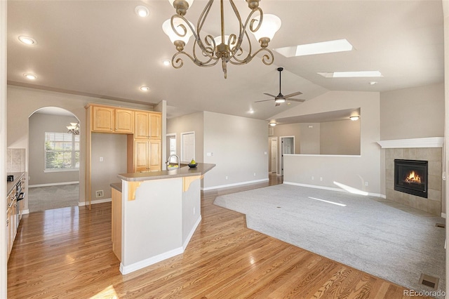 149 Walters Creek Dr, Monument, CO 80132 - kitchen with light brown cabinets, light wood-style flooring, a tiled fireplace, ceiling fan, and lofted ceiling