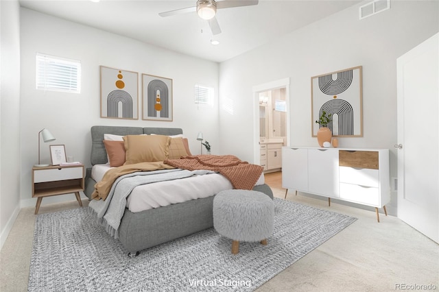 carpeted bedroom with ensuite bath and ceiling fan