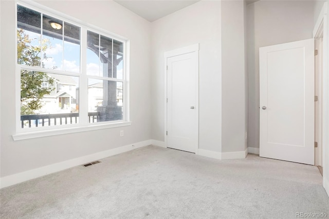 unfurnished bedroom featuring a closet, light carpet, and multiple windows