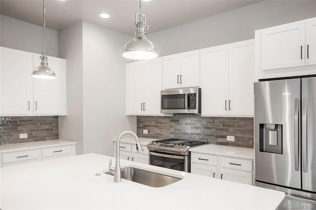 kitchen with sink, white cabinets, backsplash, hanging light fixtures, and appliances with stainless steel finishes