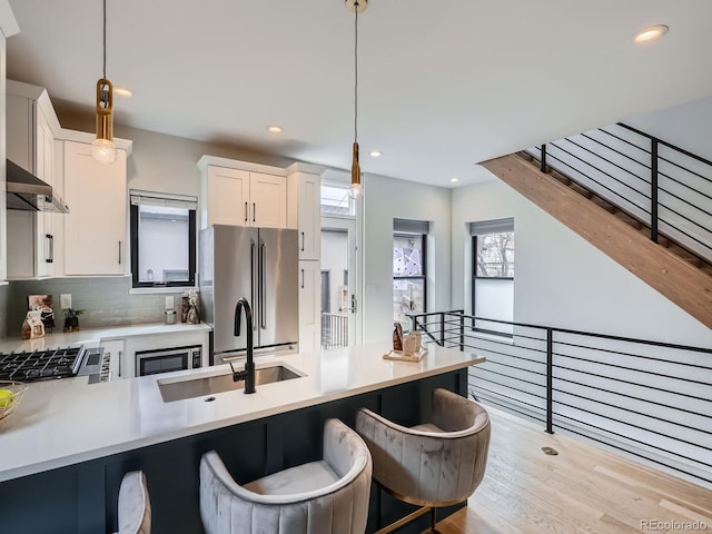 kitchen featuring backsplash, high end refrigerator, a sink, and pendant lighting