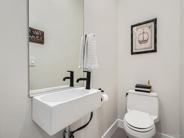 bathroom with baseboards, a sink, and toilet