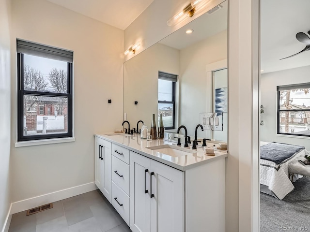 ensuite bathroom with baseboards, connected bathroom, visible vents, and a sink