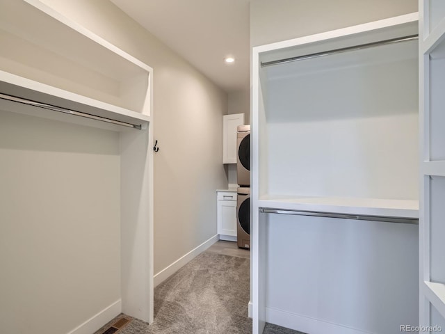 spacious closet with stacked washer / dryer and light carpet