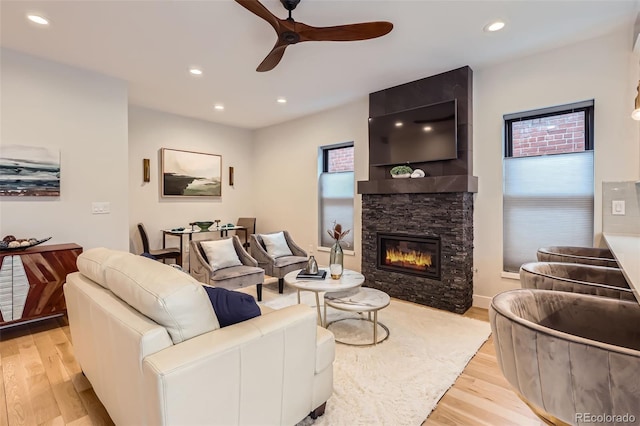 living area featuring light wood-type flooring, ceiling fan, a fireplace, and recessed lighting