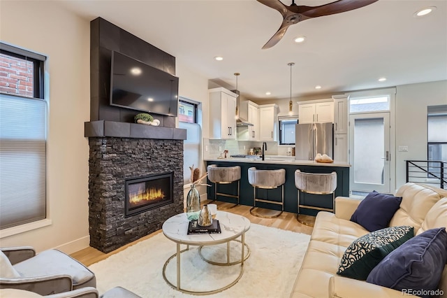 living room with a ceiling fan, a fireplace, light wood-style flooring, and recessed lighting