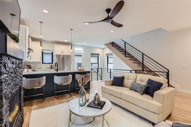 living room with stairway, recessed lighting, light wood-style flooring, and a ceiling fan