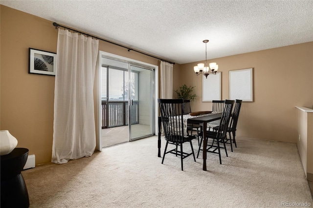 dining area with light colored carpet, a textured ceiling, and a chandelier