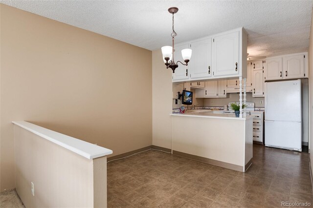 kitchen with white cabinetry, white refrigerator, kitchen peninsula, a textured ceiling, and decorative light fixtures