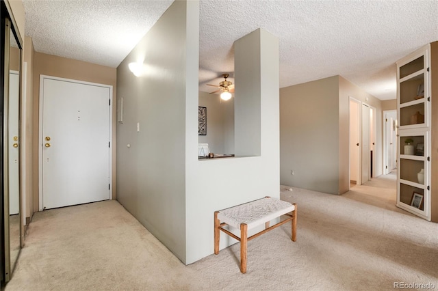 hall featuring a textured ceiling and light carpet