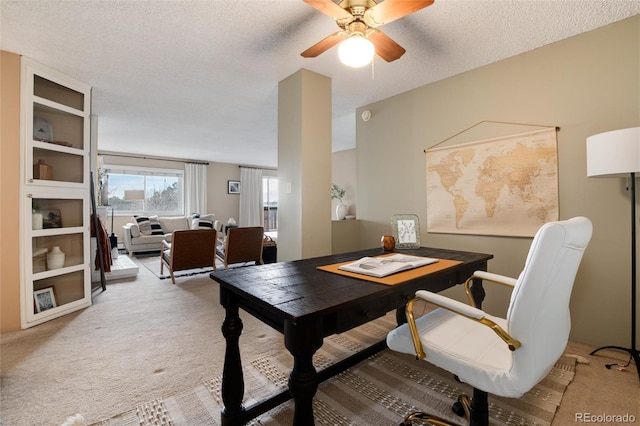 dining space featuring ceiling fan, light colored carpet, and a textured ceiling