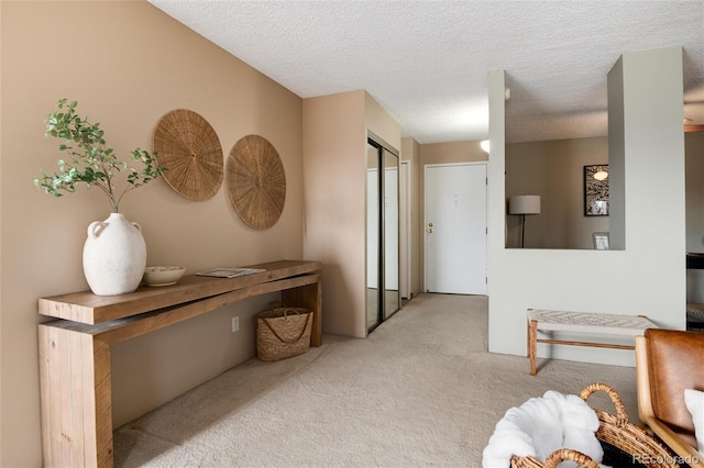 hall featuring light colored carpet and a textured ceiling