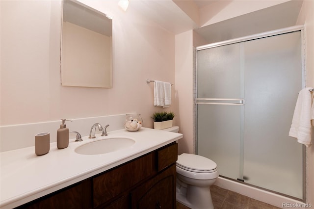 bathroom featuring tile patterned flooring, vanity, a shower with shower door, and toilet