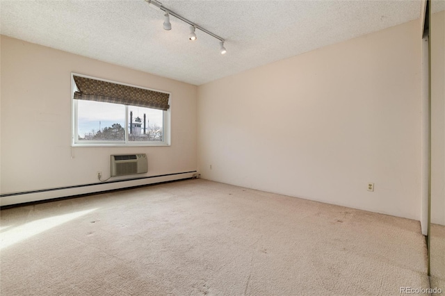 unfurnished room featuring a wall mounted air conditioner, a textured ceiling, rail lighting, and baseboard heating