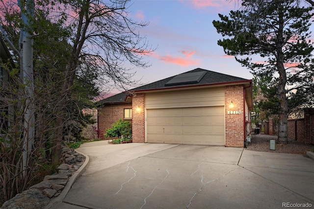 4212 E Orchard Pl, Centennial, CO 80121 - view of front of home with brick siding, concrete driveway, roof mounted solar panels, a shingled roof, and a garage