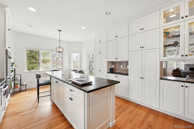 4212 E Orchard Pl, Centennial, CO 80121 - kitchen featuring dark countertops, light wood finished floors, white cabinets, recessed lighting, and tasteful backsplash