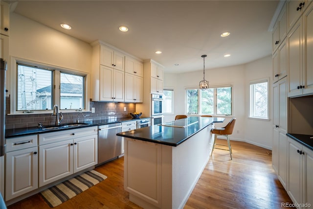 4212 E Orchard Pl, Centennial, CO 80121 - kitchen with a sink, stainless steel appliances, dark countertops, light wood-type flooring, and decorative backsplash