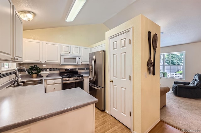 9627 Franklin St, Thornton, CO 80229 - kitchen with appliances with stainless steel finishes, vaulted ceiling, white cabinets, light wood finished floors, and a peninsula