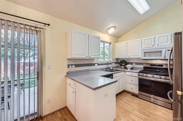 9627 Franklin St, Thornton, CO 80229 - kitchen with appliances with stainless steel finishes, a peninsula, vaulted ceiling, white cabinetry, and light wood finished floors