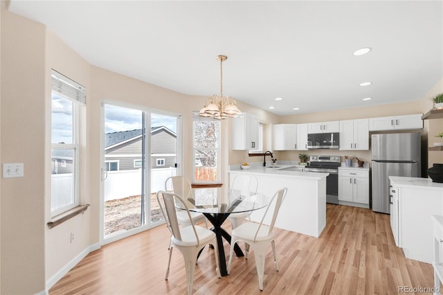 dining room featuring light wood-style flooring, plenty of natural light, a notable chandelier, and recessed lighting