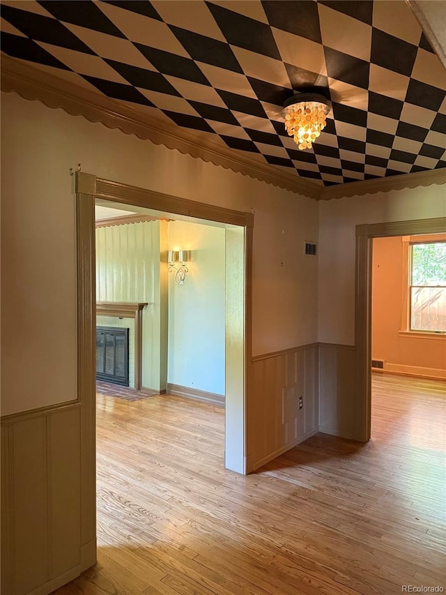 6375 E 6th Avenue Parkway, Denver, CO 80220 - unfurnished room with light wood-type flooring, a chandelier, wainscoting, and a fireplace with flush hearth