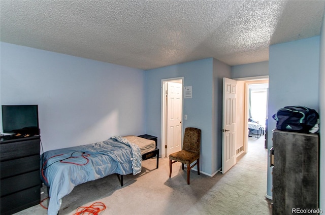 bedroom with a textured ceiling and light colored carpet