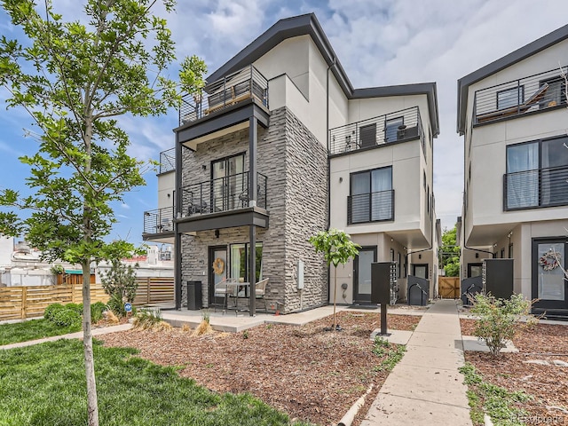 1472 Yates St, Denver, CO 80204 - view of front of property featuring stone siding, a balcony, stucco siding, and a patio area