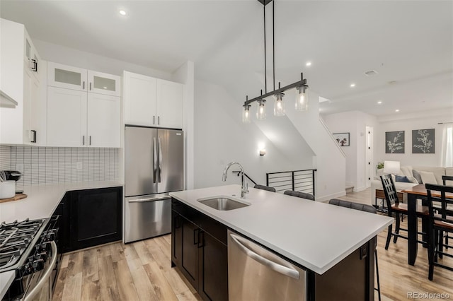 kitchen featuring backsplash, a center island with sink, sink, light hardwood / wood-style floors, and stainless steel appliances