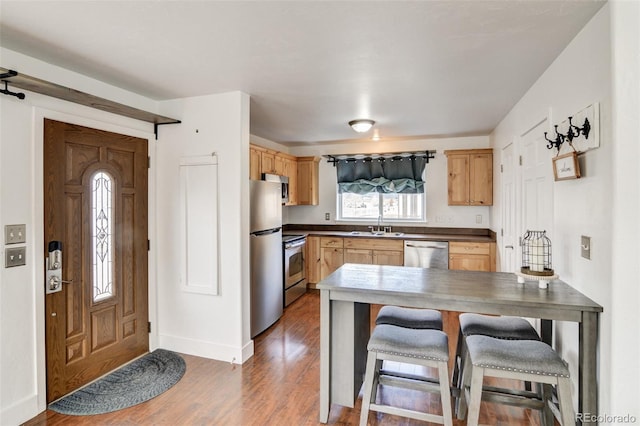 kitchen with appliances with stainless steel finishes, dark hardwood / wood-style floors, sink, a kitchen bar, and kitchen peninsula