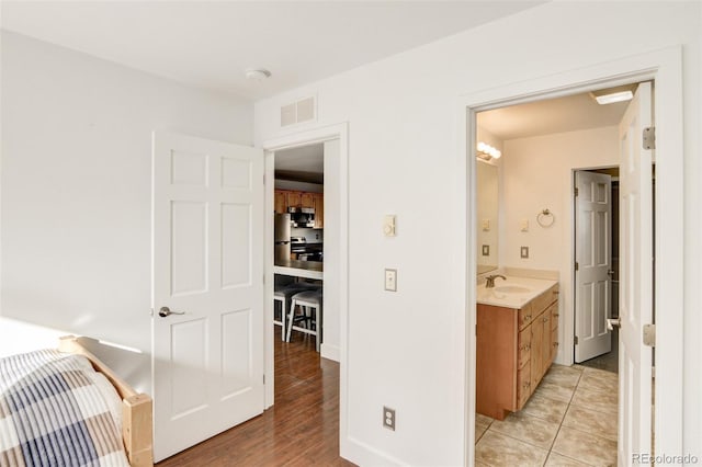 bedroom featuring stainless steel fridge, sink, and light tile patterned floors