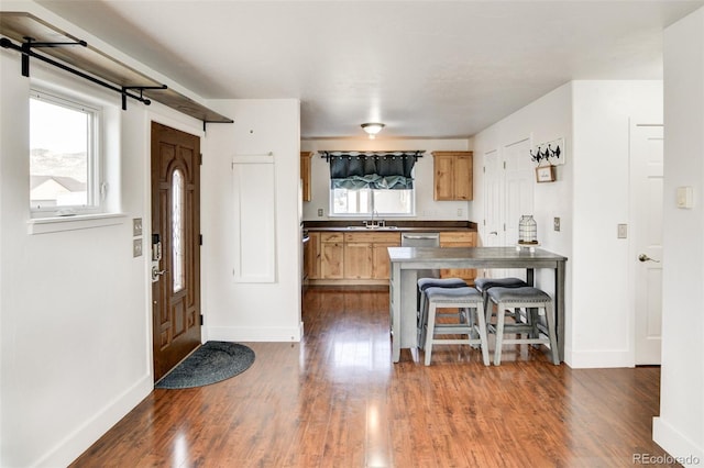 kitchen featuring a breakfast bar, light brown cabinetry, sink, dark hardwood / wood-style flooring, and dishwasher