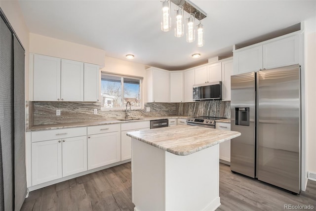 kitchen featuring stainless steel appliances, white cabinets, and decorative light fixtures