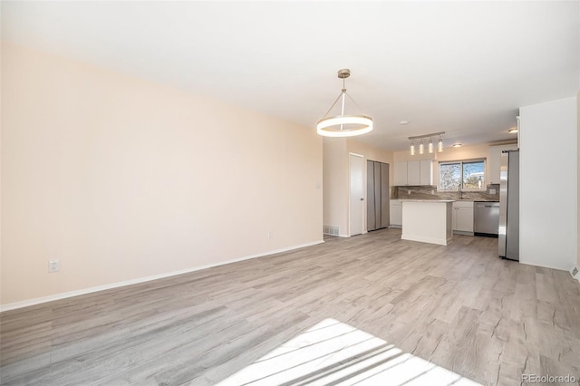 unfurnished living room featuring sink and light hardwood / wood-style flooring