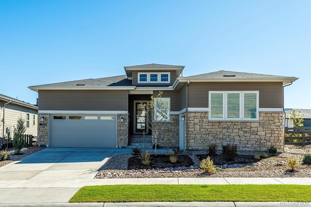 prairie-style home with an attached garage, stone siding, and concrete driveway