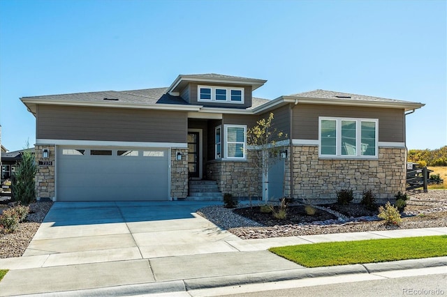 prairie-style house with a garage, concrete driveway, and stone siding