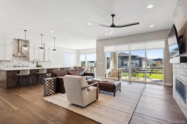 living area featuring ceiling fan, a fireplace, wood finished floors, and recessed lighting