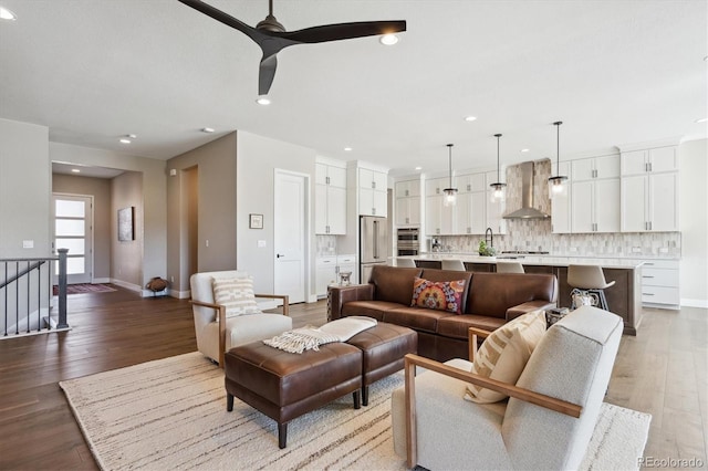 living area with light wood-type flooring, baseboards, and a ceiling fan