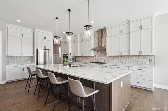 kitchen featuring white cabinetry, a large island with sink, and wall chimney exhaust hood