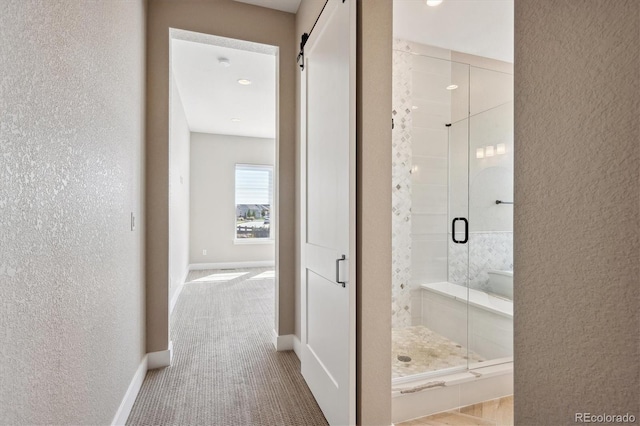 full bath with a textured wall, a shower stall, and baseboards