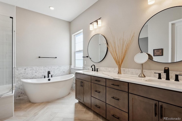 bathroom featuring double vanity, a freestanding tub, a sink, and tile walls